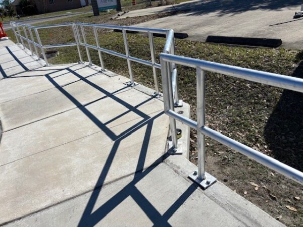 A two-row aluminum pipe with baseplate mounting or core drilled mounting. This particular installation follows the sidewalk when it juts out.
